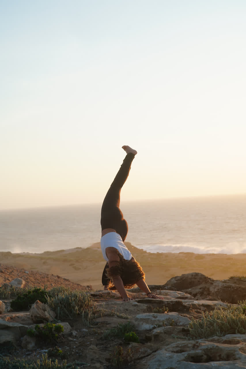 Ninas Handstand als Silhouette über dem abendlichen Ozean